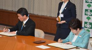 村井知事と小池都知事が合意書に記名している写真